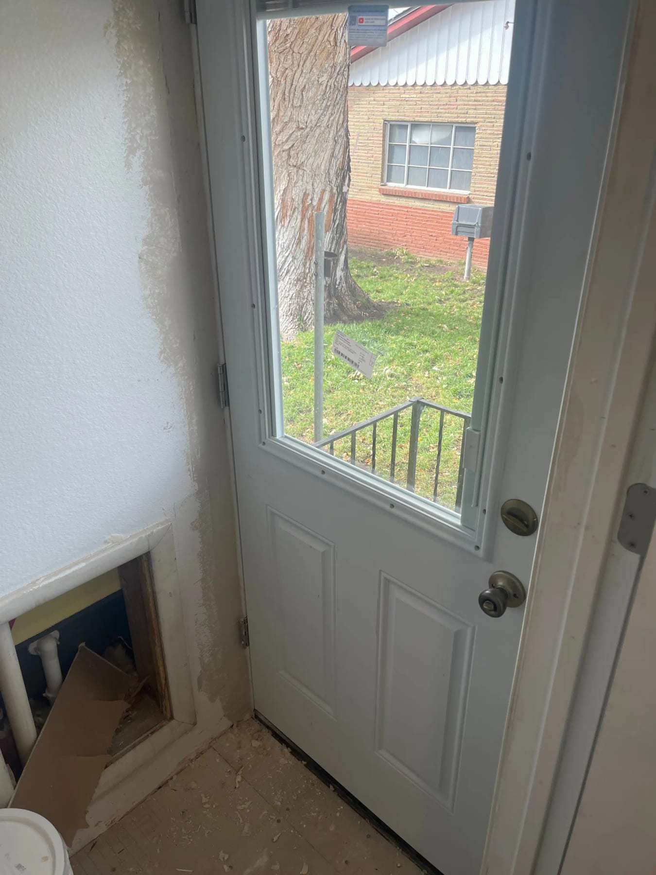 Exterior door with a damaged opening at its base and debris on the step