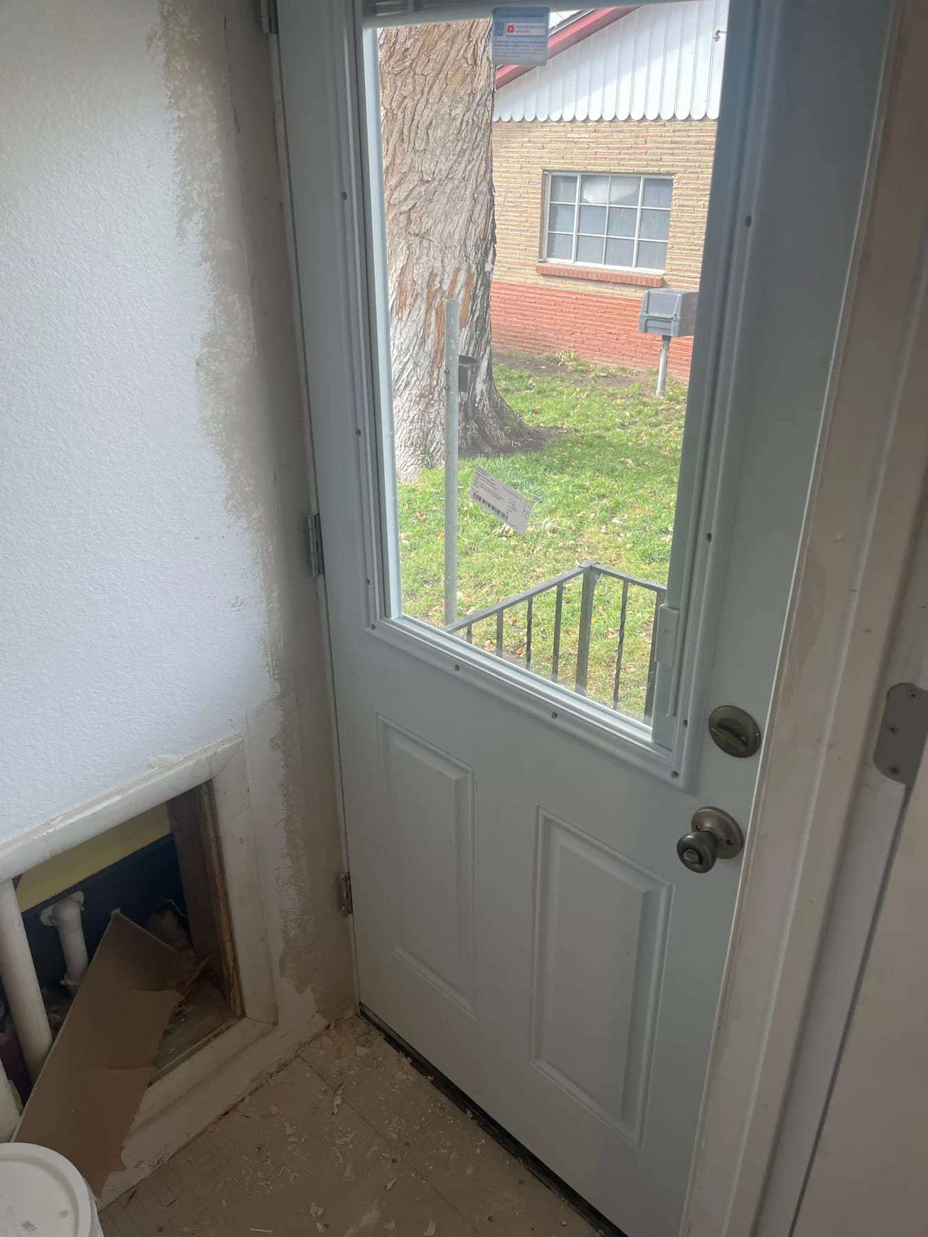 Exterior door with a damaged opening at its base and debris on the step